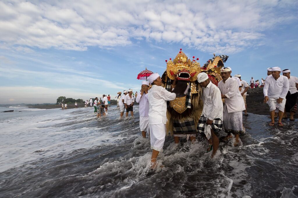 Prosesi melasti di pantai dengan payung dan umbul-umbul khas Bali
