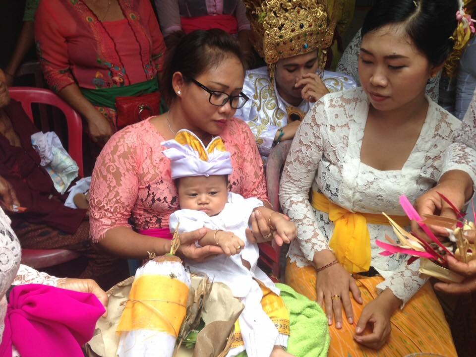 Ibu menggendong bayi dalam upacara nelu bulanin adat Bali
